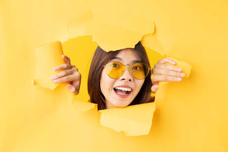 full body portrait of playful asian girl lying on blue backgroundの写真素材