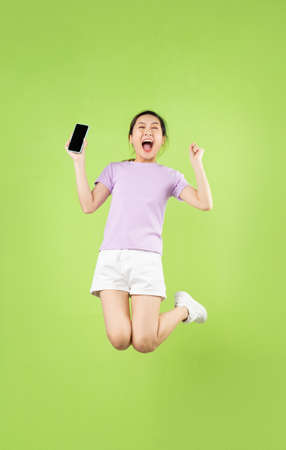 Full body Young Asian girl jumping, isolated on green backgroundの写真素材