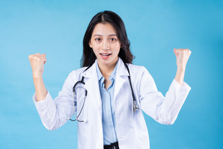 portrait of young female doctor, isolated on blue backgroundの写真素材