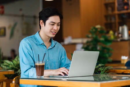 Asian man sitting and drinking coffeeの写真素材