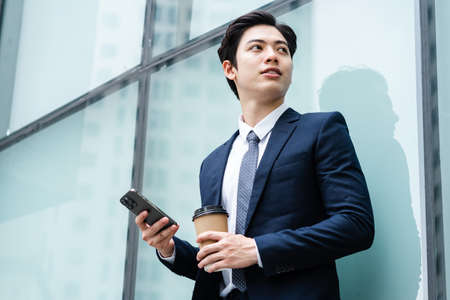 Image of Young asian businessman with glass building backgroundの写真素材
