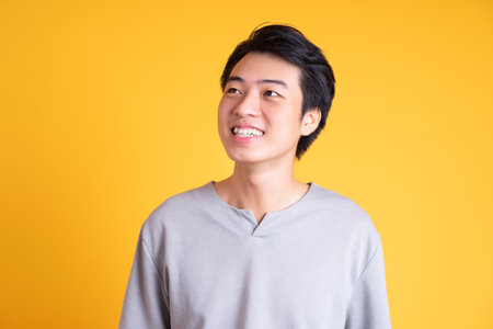 Asian young man posing on a yellow backgroundの写真素材
