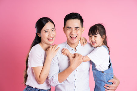 happy young asian family image, isolated on pink backgroundの写真素材