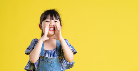 portrait of a beautiful asian girl, isolated on yellow backgroundの写真素材