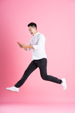 Asian man full body image, isolated on pink backgroundの写真素材