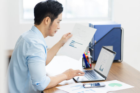 Asian businessman male portrait sitting at his deskの写真素材