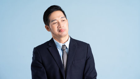 portrait of asian businessman wearing suit on blue backgroundの写真素材