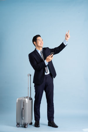 Portrait of Asian businessman wearing a suit and pulling a suitcaseの写真素材