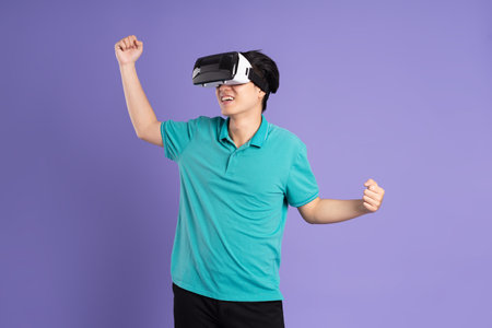 image of asian man wearing virtual reality glasses on purple backgroundの写真素材