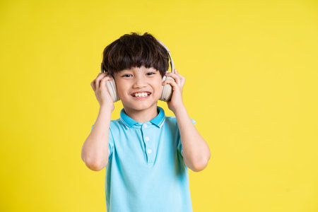portrait of an asian boy posing on a yellow backgroundの写真素材