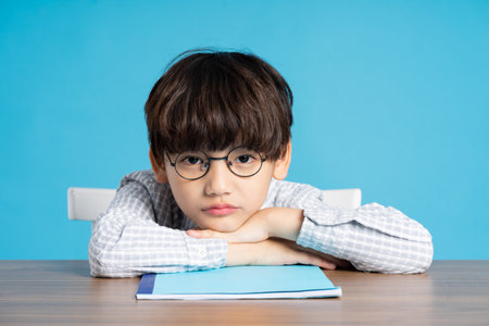 portrait of school boy sitting and studying on a blue background