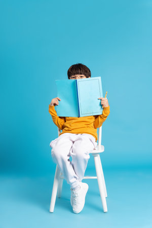 Portrait of sitting boy, isolated on blue backgroundの写真素材