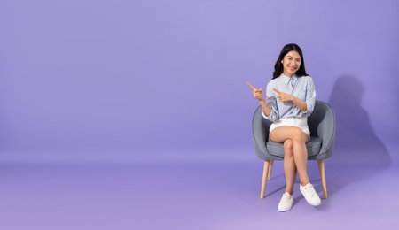 image of girl sitting on sofa  isolated on purple backgroundの写真素材