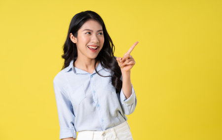 portrait of beautiful asian girl posing on yellow backgroundの写真素材