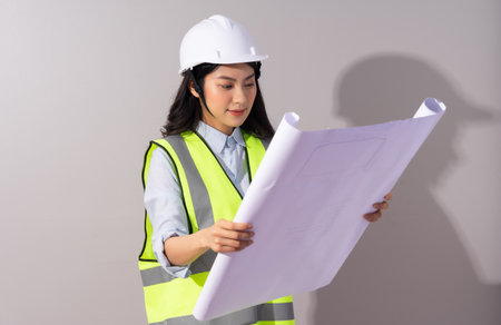 image of female architect looking at blueprints on gray backgroundの写真素材
