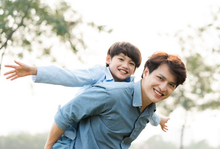 image of an asian father and son having fun in the parkの写真素材