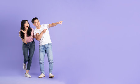 full body image of asian couple posing on purple backgroundの写真素材
