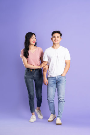 full body image of asian couple posing on purple backgroundの写真素材