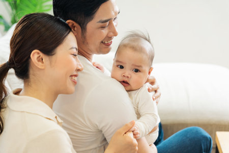 Smiling mother and father holding newborn son at homeの写真素材