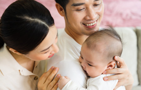 Smiling mother and father holding newborn son at homeの写真素材