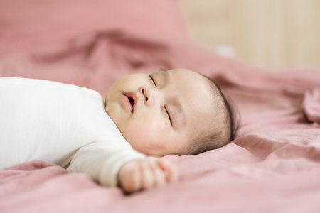 image of a newborn baby lying on a pink bedの写真素材
