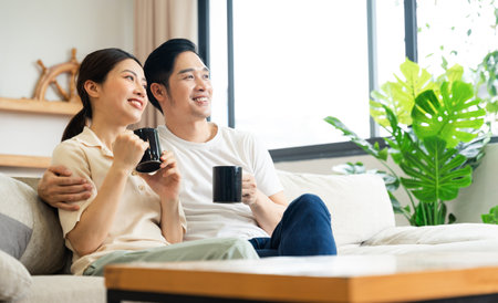 image of asian couple sitting on sofa at homeの写真素材