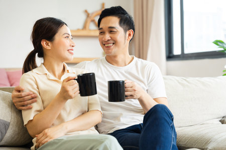image of asian couple sitting on sofa at homeの写真素材