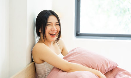 Portrait of a beautiful and playful asian girl in bed in the morningの写真素材