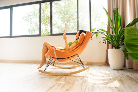 image of asian girl relaxing on a chair at her houseの写真素材