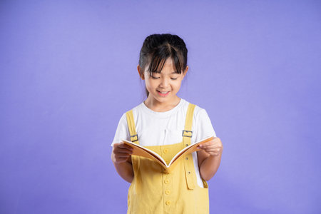cute asian schoolgirl posing on purple backgroundの写真素材
