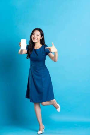 Portrait of beautiful woman in blue dress, isolated on blue backgroundの写真素材
