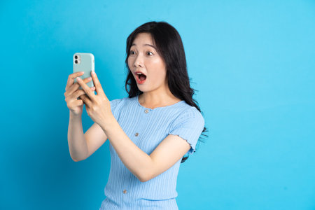 Portrait of smiling asian woman posing on blue backgroundの写真素材