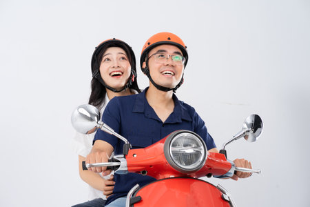 A couple wearing helmets and riding a motorbike
