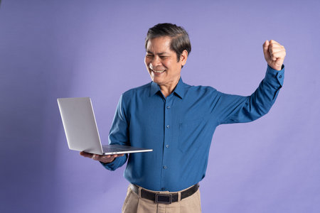 portrait of middle aged asian business man posing on purple background