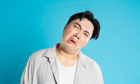 Portrait of an Asian guy posing on a blue backgroundの写真素材