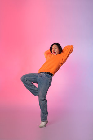 Image of a young Asian person dancing on a neon colored backgroundの写真素材