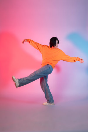 Image of a young Asian person dancing on a neon colored backgroundの写真素材