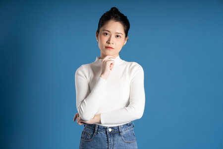 Portrait of beautiful asian woman posing on blue backgroundの写真素材