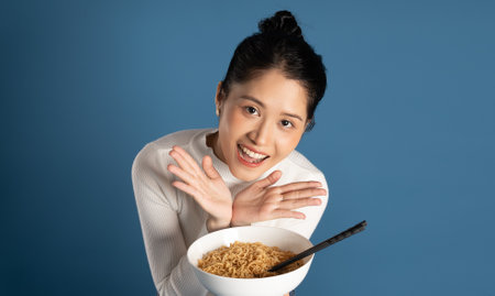 Portrait of beautiful asian girl posing on blue backgroundの写真素材