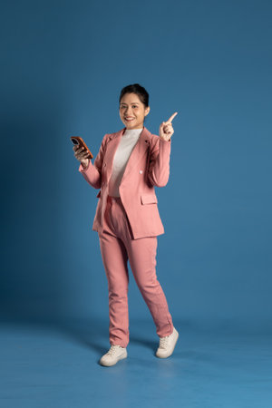 Portrait of young businesswoman standing and posing isolated on blue backgroundの写真素材