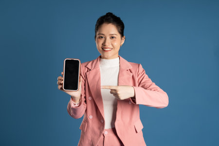 Portrait of young Asian businesswoman posing isolated on blue backgroundの写真素材