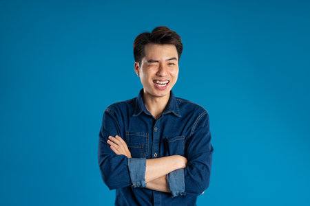 Portrait of young Asian business man posing on blue backgroundの写真素材