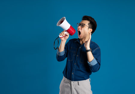 Portrait of young Asian business man posing on blue backgroundの写真素材