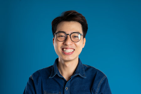 Portrait of young Asian business man posing on blue backgroundの写真素材