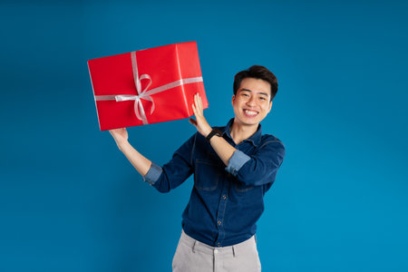 Portrait of young Asian business man posing on blue backgroundの写真素材