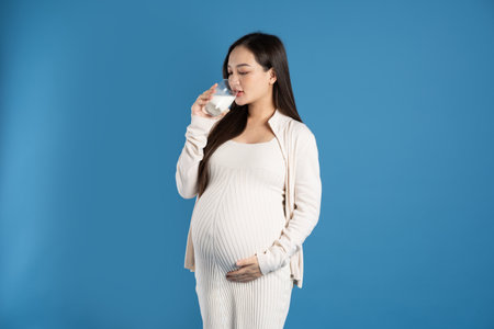 Portrait of pregnant asian woman, isolated on blue background