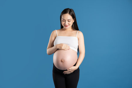 Portrait of pregnant asian woman, isolated on blue backgroundの写真素材