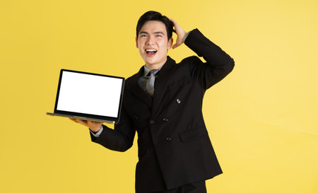 Portrait of Asian male businessman. wearing a suit and posing on a yellow backgroundの写真素材