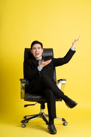 Portrait of Asian male businessman. wearing a suit and posing on a yellow backgroundの写真素材