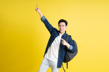 Portrait of Asian male student posing on yellow backgroundの写真素材
